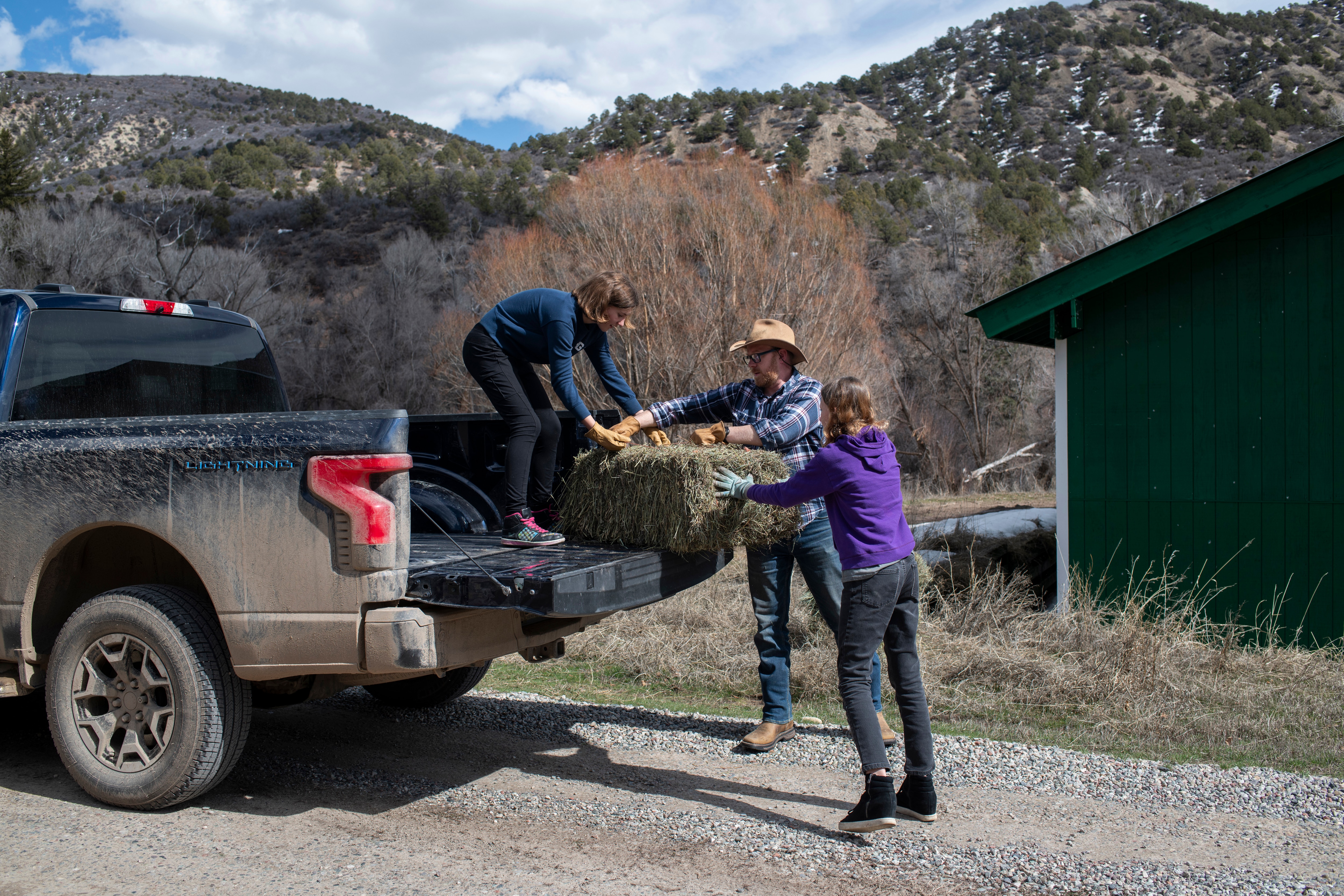 Ben Westby, center, lifts bales of hay with his daughters, Ari Westby, 12, left, and Lizzie Westby, 13, right, into the bed of their Ford F-150 Lightning on Sunday, March 17, 2024 in New Castle, Colorado. Rachel Woolf for Ford